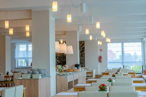 a dining room with white tables and chairs and chandeliers at Hotel *** NAT Jarosławiec in Jarosławiec