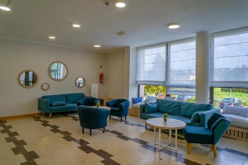 a living room with blue couches and chairs at Hotel *** NAT Jarosławiec in Jarosławiec