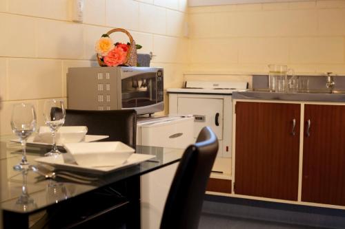 a kitchen with a table with glasses of wine at Broadway Motel & Miro Court Villas in Matamata