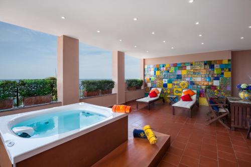 une grande chambre avec bain à remous dans une maison dans l'établissement Hotel Caparena, à Taormine