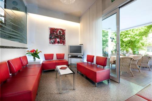 a living room with red couches and a television at Hotel Felix in Rimini