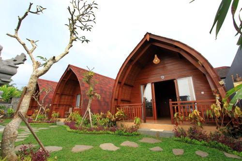 uma pequena casa de madeira com um jardim em frente em Pondok Naya - CHSE Certified em Ubud