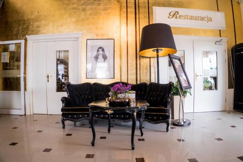 a room with chairs and a table with flowers on it at Hotel Luxor in Lublin