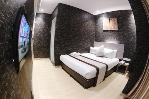 a bedroom with a large bed and a tv at Here Hotel in Skudai