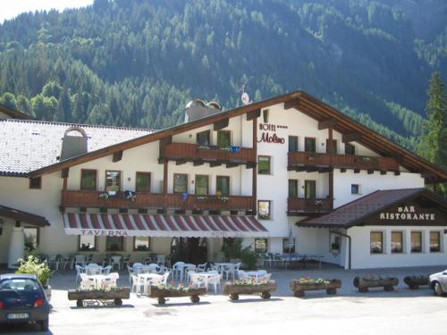 a large building with tables and chairs in a parking lot at Hotel Molino in Falcade