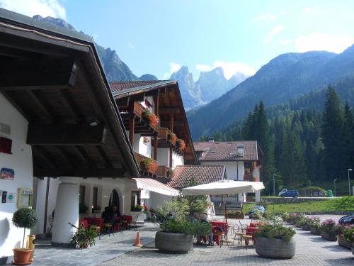 a building with tables and chairs and umbrellas at Hotel Molino in Falcade