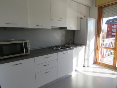 a kitchen with white cabinets and a microwave and a window at Assago Forum Apartment in Assago