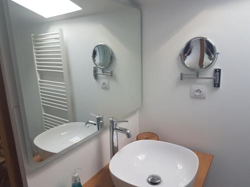 La salle de bains est pourvue d'un lavabo blanc et d'un miroir. dans l'établissement L'Angélus, à Genay