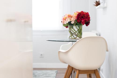 a white chair with a vase of flowers on a table at NC APARTMENT in Santiago de Compostela