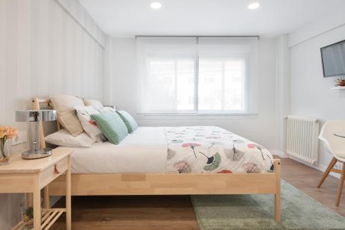 een witte slaapkamer met een bed en een raam bij NC APARTMENT in Santiago de Compostela