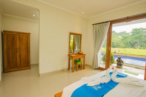 a bedroom with a bed and a large window at The Carik Bisma Ubud in Ubud