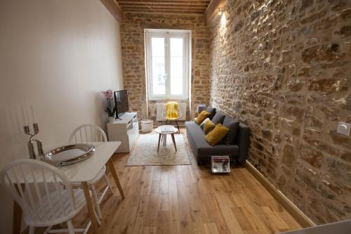 un salon avec un canapé et un mur de briques dans l'établissement Hamac Suites - Studio Ainay 4 - Hyper centre Lyon, à Lyon