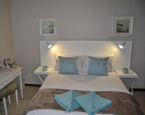 een slaapkamer met een groot wit bed met blauwe kussens bij Hamilton Urban Farm Guest House in Pietermaritzburg