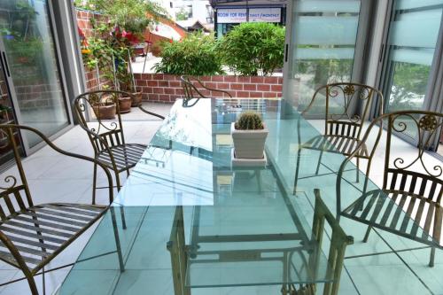 a glass table and chairs on a patio at Baan Petcharat in Patong Beach