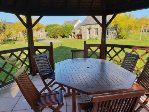 une table et des chaises en bois assises sur une terrasse couverte dans l'établissement lesroses1680, à Blainville-sur-Mer