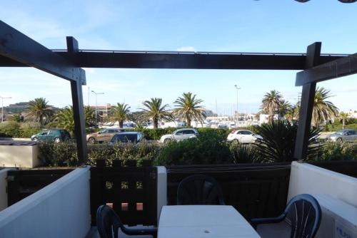 d'une terrasse avec une table et des chaises, ainsi que d'un parking. dans l'établissement Cap Agde Village naturiste Port Nature, au Cap d'Agde