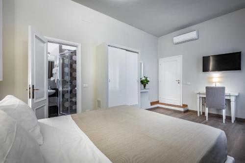 a white bedroom with a bed and a desk and a television at Blu Notte Guest House in Florence