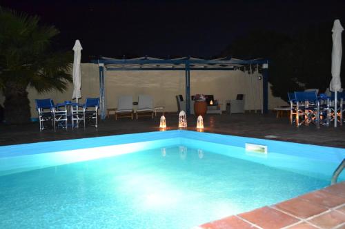 a swimming pool at night with a table and chairs at Melina Hotel in Fira