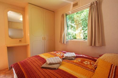 a bed in a bedroom with a window and a bedspread at Mobilhome Markgrafenheide für Familie und Monteure in Markgrafenheide