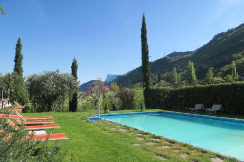 a swimming pool in a yard with chairs and trees at Garni Hotel Burgleitenhof in Lana