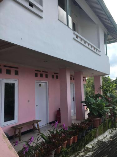 a pink and white building with a bench and plants at Hotel Wijaya 1 Kaliurang in Yogyakarta
