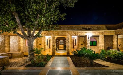 una casa de piedra con un árbol en el patio en Hotel Rawalkot Jaisalmer, en Jaisalmer