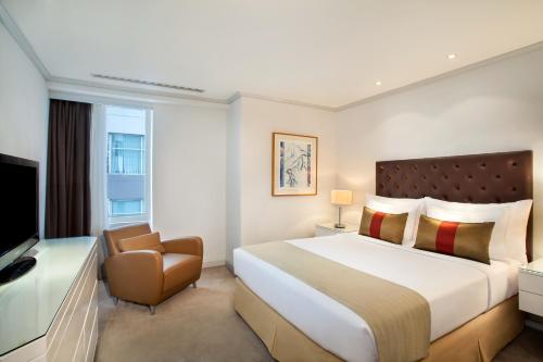 a hotel room with a large bed and a chair at Wyndham Casablanca Jakarta in Jakarta