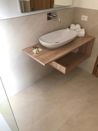 a bathroom with a white sink on a wooden shelf at Garni Hotel Burgleitenhof in Lana