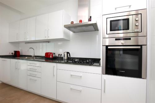 cocina blanca con armarios blancos y microondas en Apartamento s' Estanyol Mar, en El Estanyol