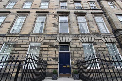 a stone building with a blue door and windows at Escape To Edinburgh @ Albyn Place in Edinburgh