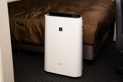 a white refrigerator sitting on the floor next to a bed at Sanco Inn Yokkaichi Ekimae in Yokkaichi
