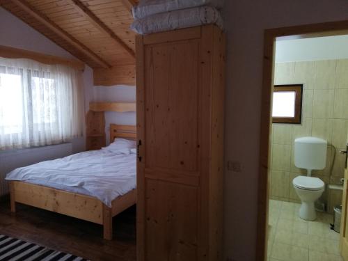 a bedroom with a bed and a toilet in a room at Pensiunea L`Amoro in Neagra Şarului