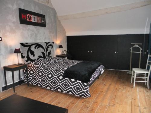 a bedroom with a black and white bed and a chair at LA RENAUDIERE in Dancé