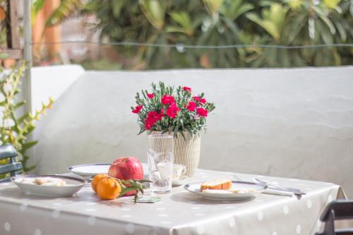 a table with plates of food and a vase with red flowers at B&B Nell'Isola in Carloforte
