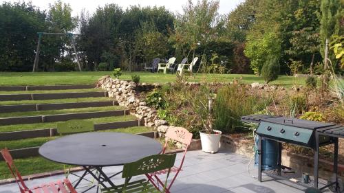 a patio with a table and chairs and a grill at LA RENAUDIERE in Dancé