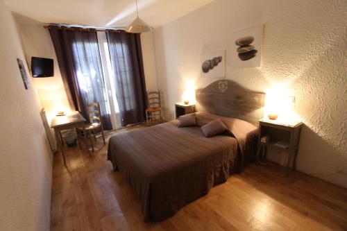 a bedroom with a large bed and two lamps at Logis Hôtel Castel Mouisson in Barbentane