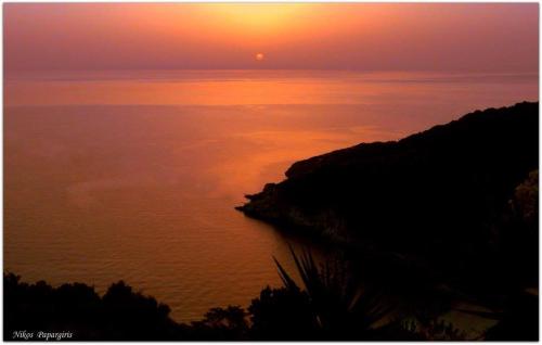 a sunset over a body of water with the sun setting at Dimosthenis Karastamatis Rooms in Xorychti
