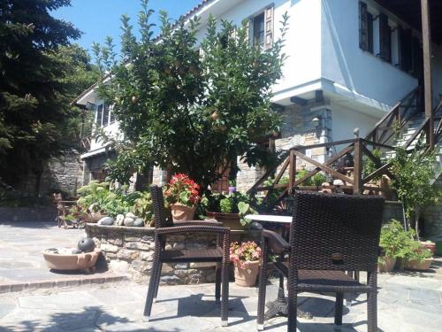 two chairs and a tree in front of a house at Dimosthenis Karastamatis Rooms in Xorychti