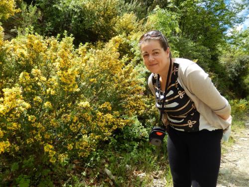 a woman standing next to a bush with a camera at Dimosthenis Karastamatis Rooms in Xorychti