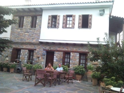 two people sitting at a table in front of a building at Dimosthenis Karastamatis Rooms in Xorychti
