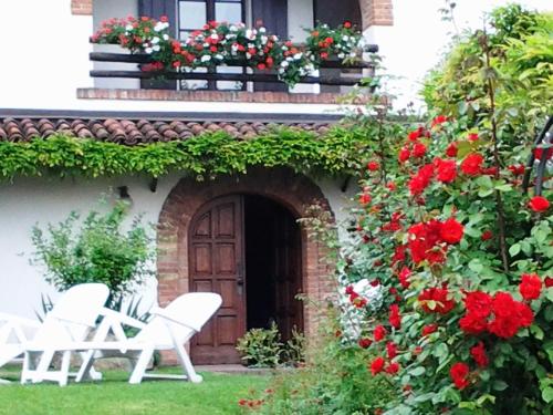 a group of white chairs in front of a house with red flowers at Bed And Breakfast Olimpia in San Salvatore Monferrato