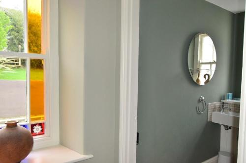 a bathroom with a mirror and a vase next to a window at Michaelstow in Perranporth