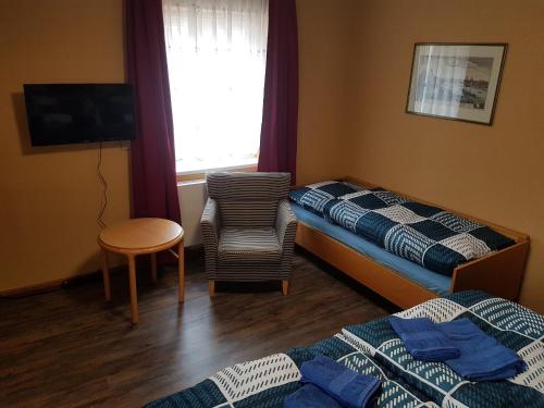 een hotelkamer met 2 bedden, een stoel en een raam bij Ferienhaus Wohnen unter Freunden in Arnstadt