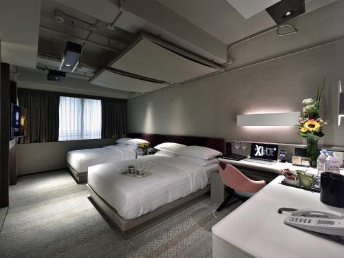 una camera d'albergo con due letti e una scrivania di Xi Hotel a Hong Kong