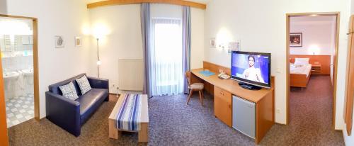 a hotel room with a television and a living room at Kurhotel Anders in Bad Füssing