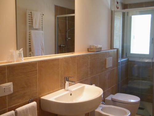 a bathroom with a sink and a toilet and a mirror at Bed & Breakfast Le Coste in Lazise