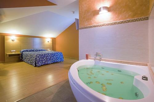 a bathroom with a bath tub and a bedroom at Hotel Los Pasiegos in Hoznayo