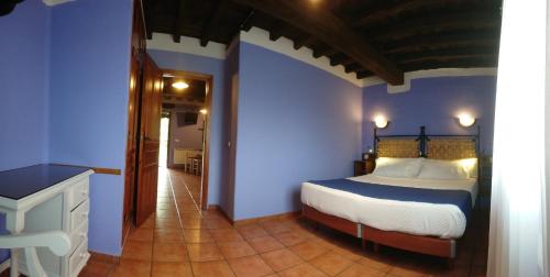 a bedroom with a bed in a blue room at El Canchal de la Gallina - Piscina de agua caliente hasta 15 de octubre in Hervás