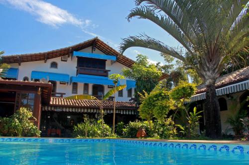 a resort with a swimming pool in front of a building at Pousada do Marujo in Rio das Ostras
