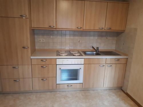 a small kitchen with wooden cabinets and a sink at Preisbewusste Ferienwohnung für 2 Personen u. Kleinkind in Utarp